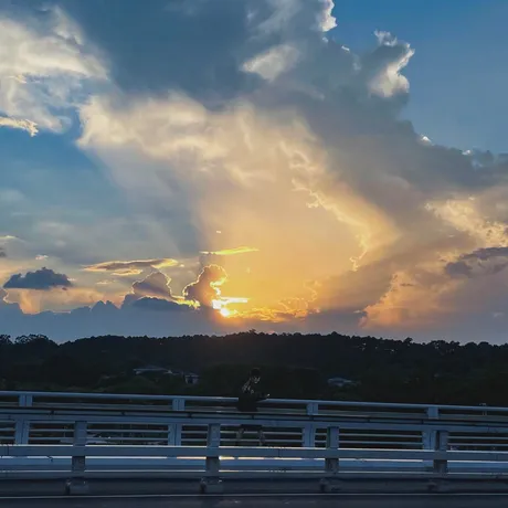 Sunset breaking through storm clouds above a bridge